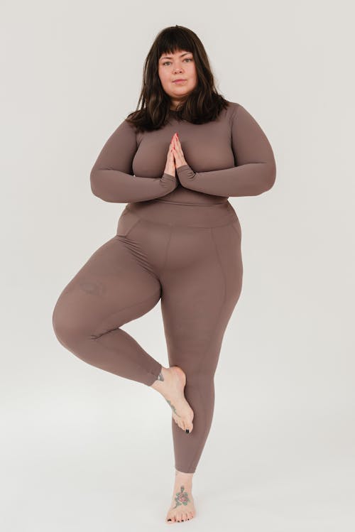 Free Overweight young woman practicing Tree asana during yoga lesson Stock Photo