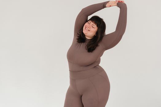 Overweight smiling woman in sportswear with raised arms