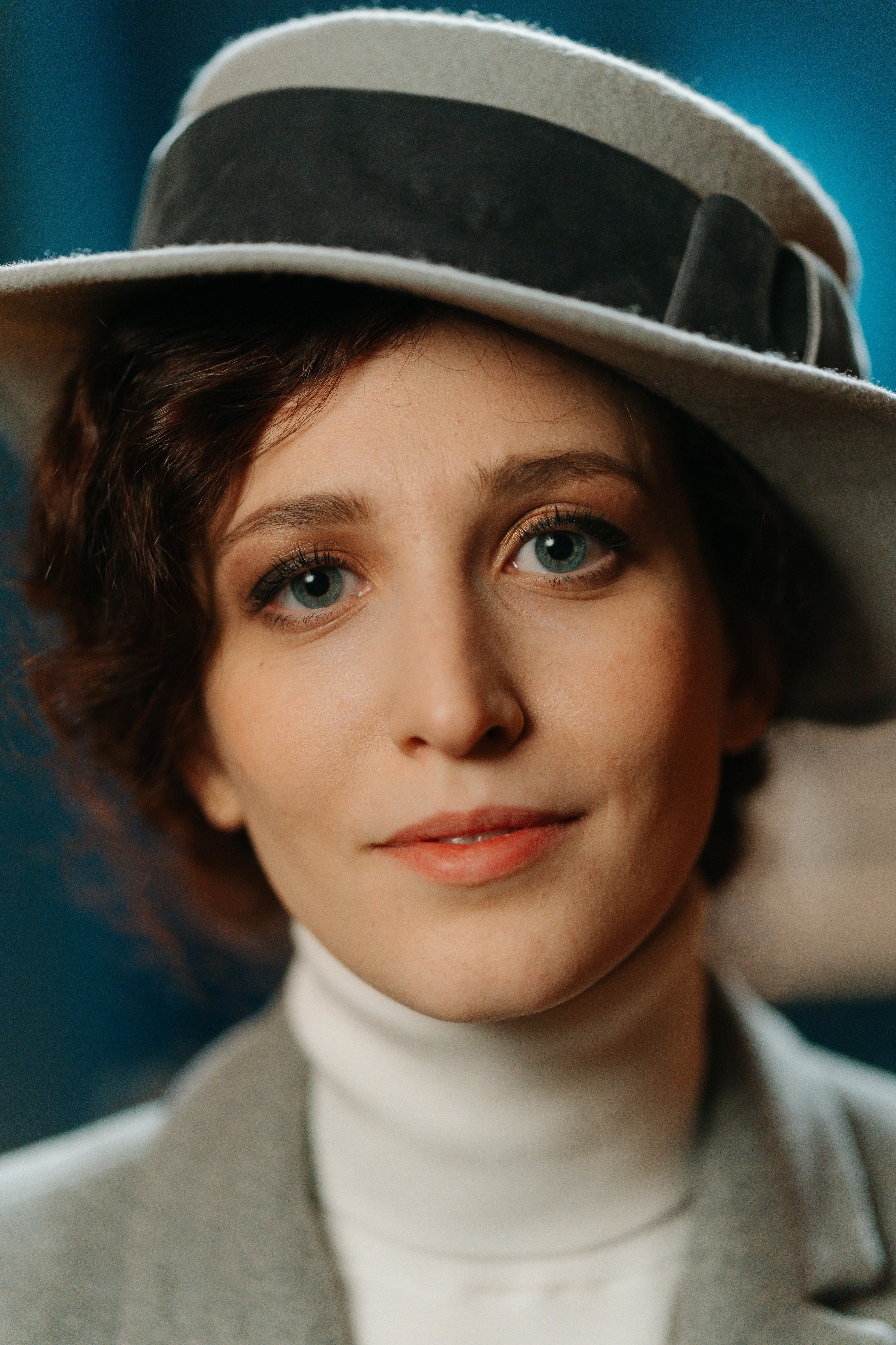 Close-up portrait of a woman in a stylish vintage hat with subtle lighting.