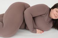 Smiling woman in activewear lying on floor in studio