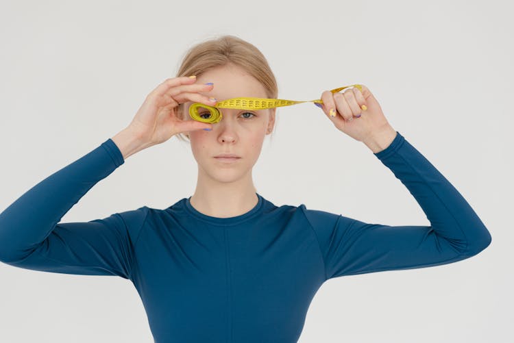 Serious Woman With Rolled Measuring Tape In Studio