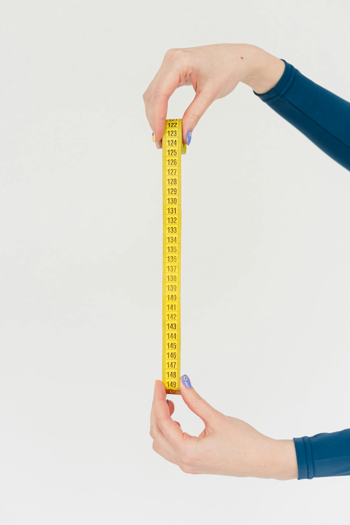 Hands holding a yellow measuring tape on a white background, symbolizing precision