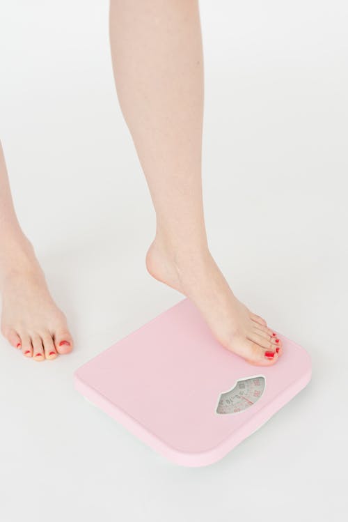 Free Woman getting on scales in studio Stock Photo