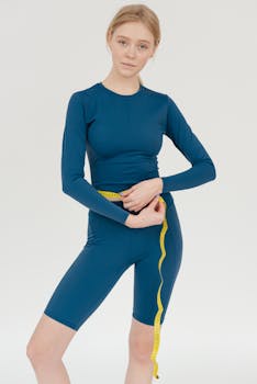 Young woman in blue activewear using a measuring tape, promoting healthy lifestyle and body care.