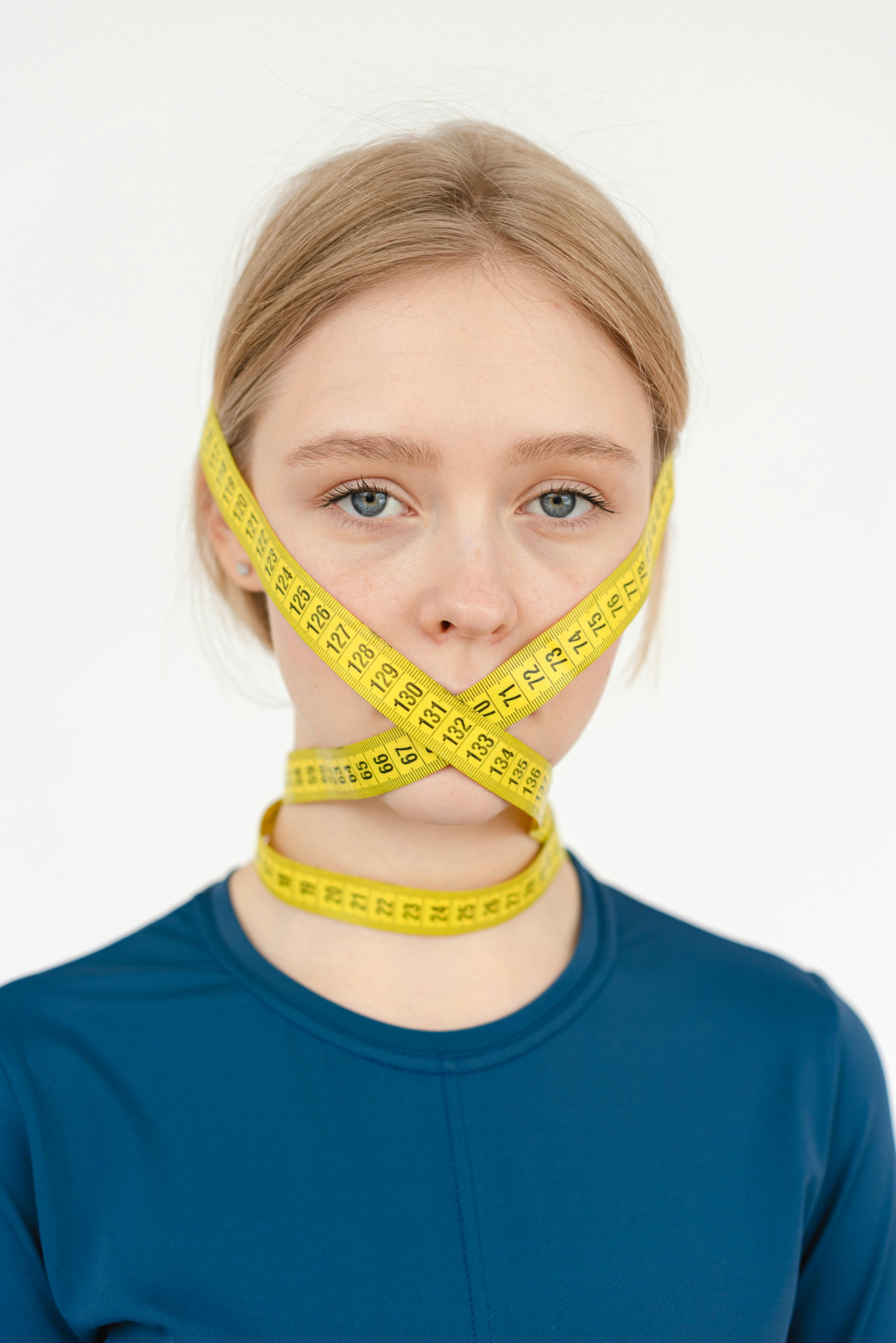 unhappy woman covering face with centimeter tape