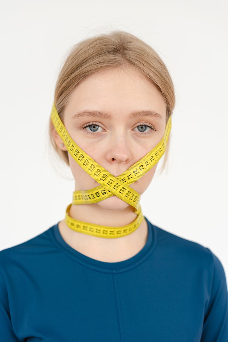 Unhappy Woman Covering Face With Centimeter Tape