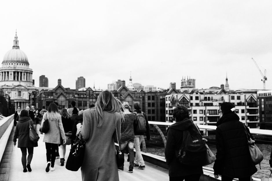 Black and white city scene with people walking on a bridge, iconic dome visible.