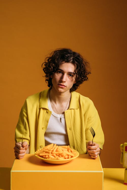 Young Man With A Sad Face Sitting By The Table With Food