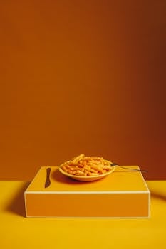 Brightly colored plate of crispy french fries on an orange background, emphasizing vibrant food presentation.