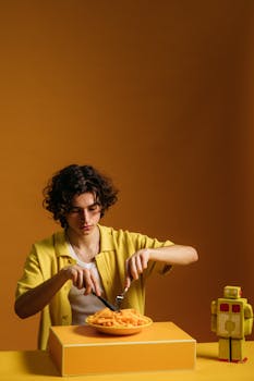 Curly-haired young man in retro setting enjoying French fries.