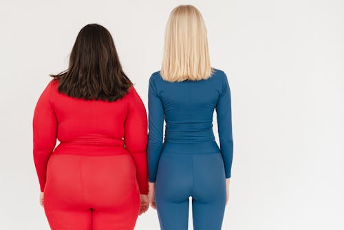 Unrecognizable women with different body types Stock Photo, thinner in blue while plus-sizer in red