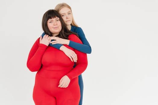 Two women embracing in colorful sportswear, expressing confidence and body positivity.