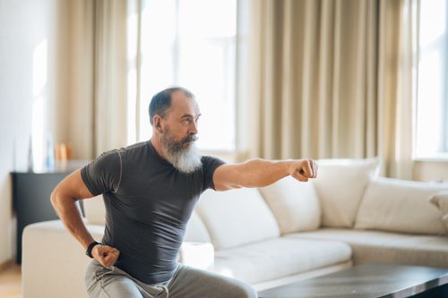 Free Elderly man with a beard performing yoga poses indoors, promoting health and wellness. Stock Photo