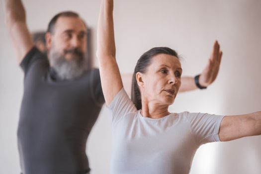 Senior adults in a yoga session indoors, focusing on stretching and balance.
