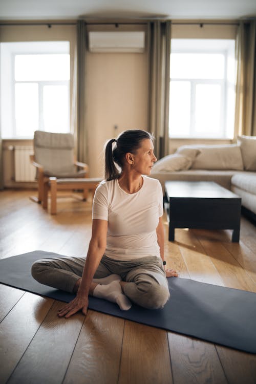 Free A Woman in the Living Room Sitting on the Yoga Mat Stock Photo