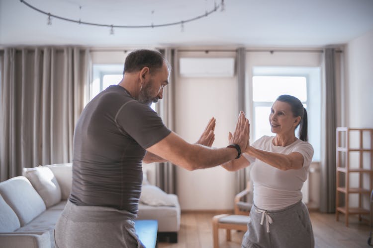 A Man And A Woman Doing Yoga With Their Hands Together