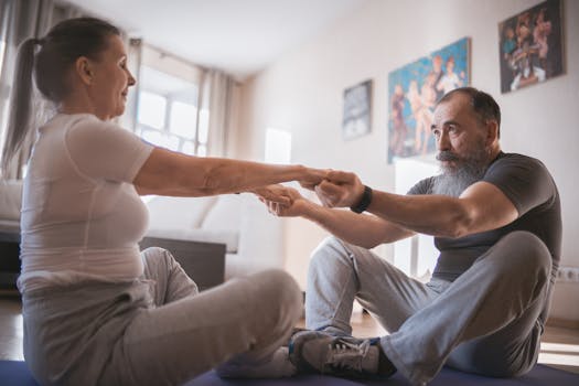 Elderly couple practicing yoga together on mats in a cozy living room setting.