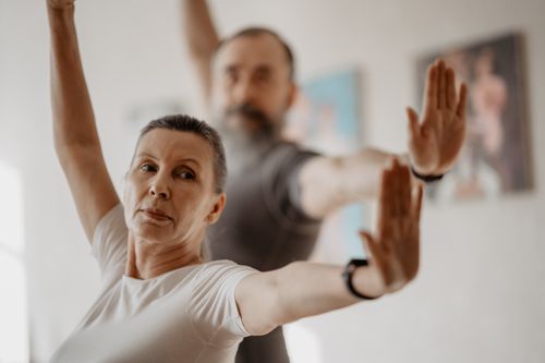Free Elderly couple stretching arms in yoga pose indoors for fitness. Stock Photo