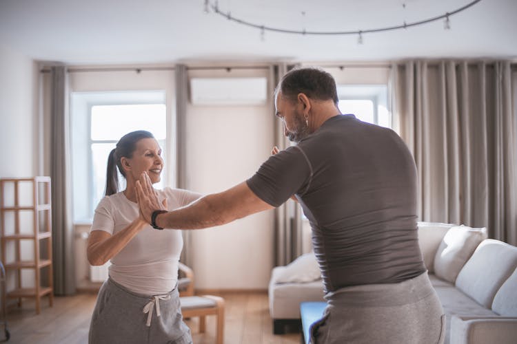 A Mature Couple Doing Yoga Pressing Hands Together