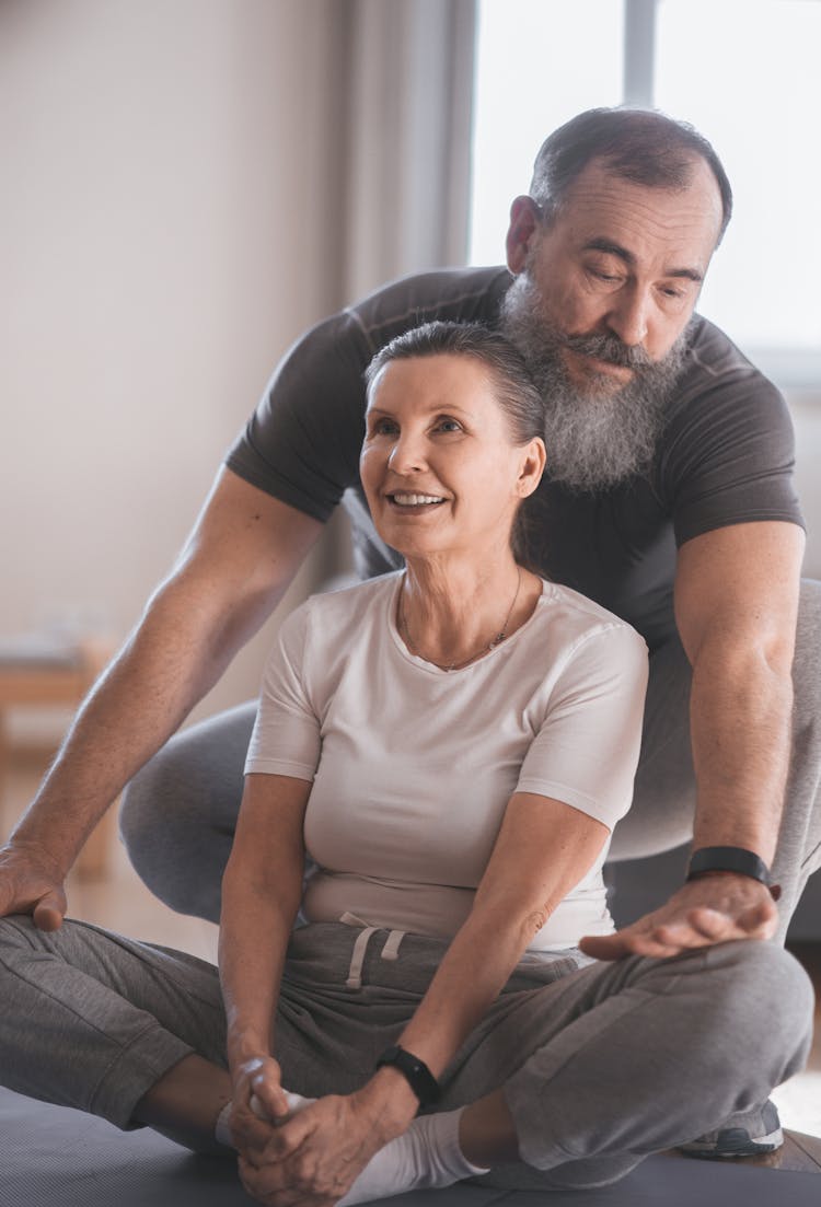 An Elderly Man Assisting Her Partner While Doing Yoga