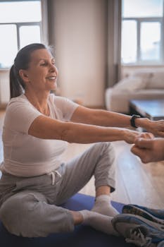 A happy senior woman stretching on a yoga mat indoors, promoting health and well-being.