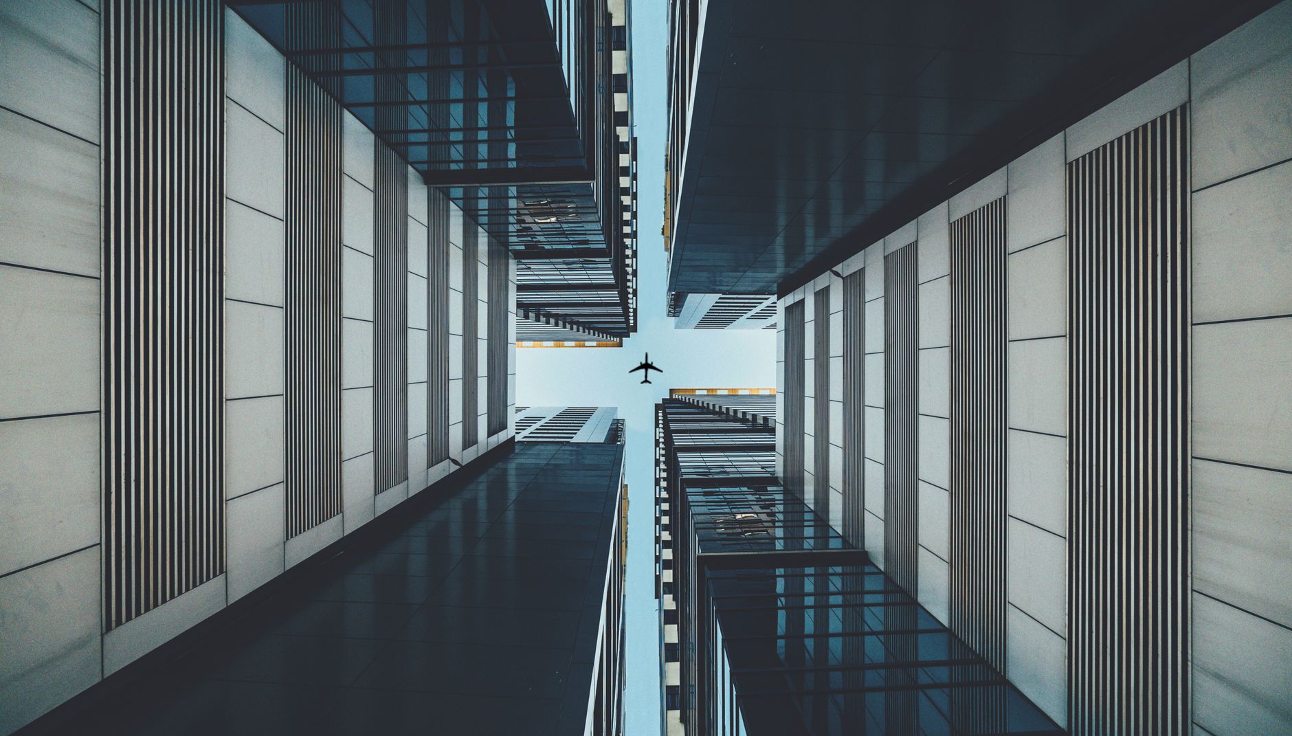 View of an airplane flying above skyscrapers in a city with a modern architectural design.