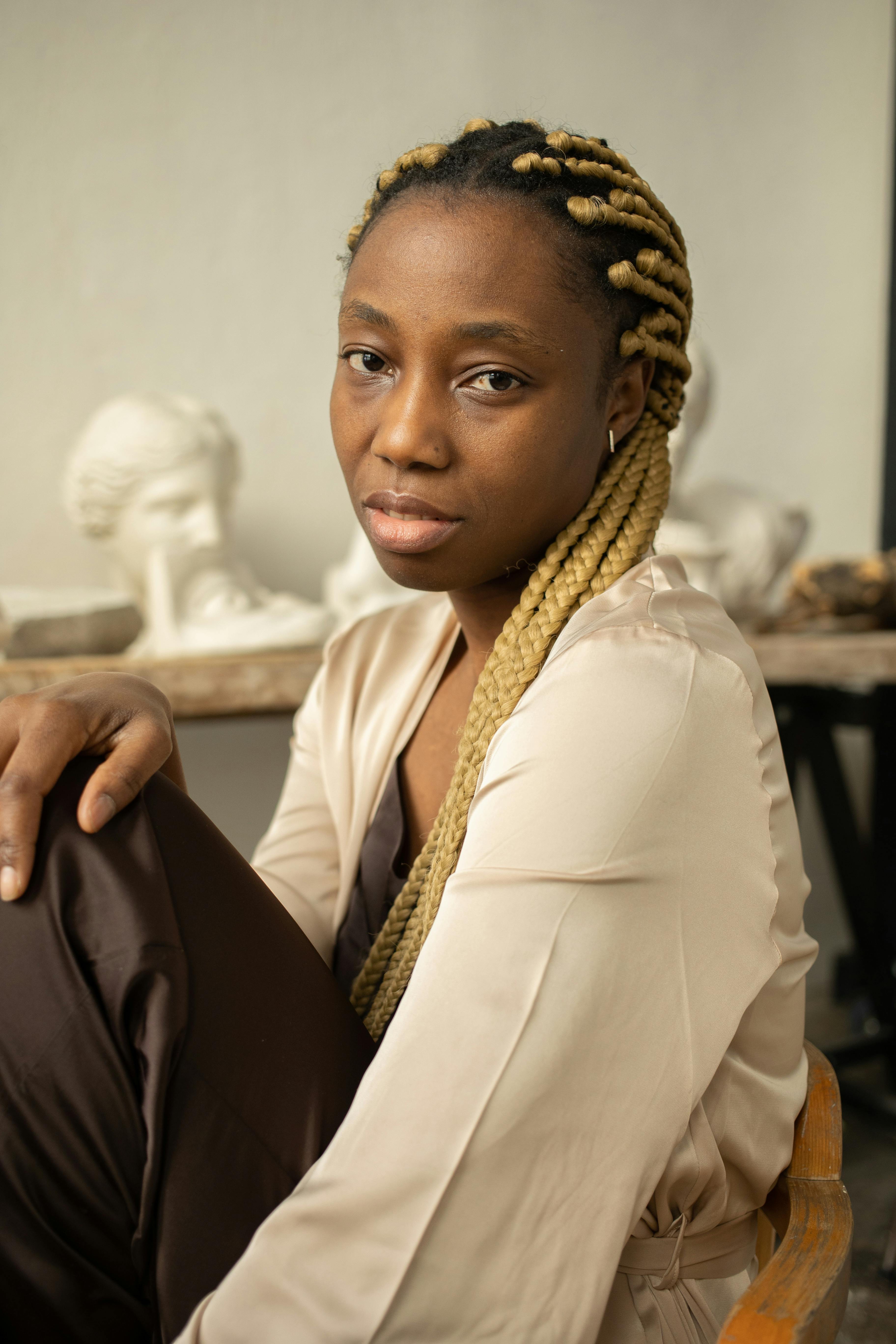 Close-up portrait of a woman with blonde dreadlocks in a studio setting, exuding confidence and calmness.