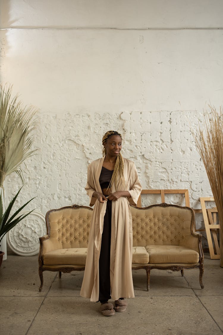 A Woman Wearing A Robe While Standing Near The Couch