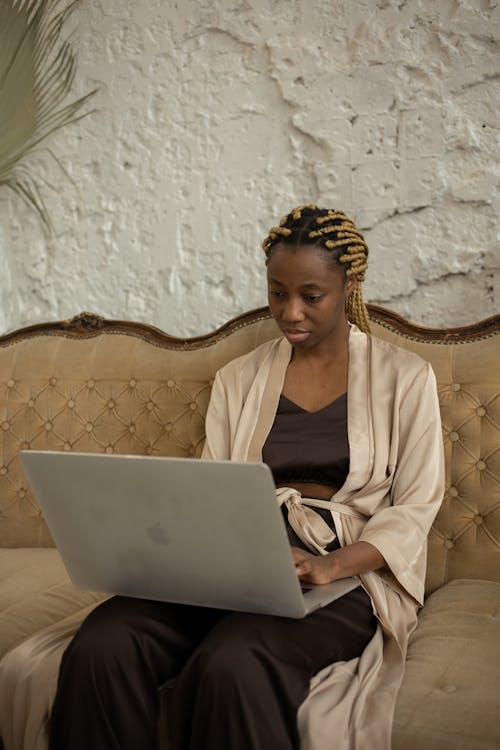 A Woman Sitting on the Couch while Using Her Laptop