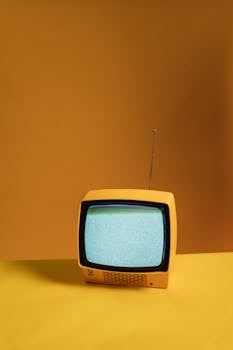 Vintage yellow television with static screen on an orange backdrop creating a nostalgic vibe.
