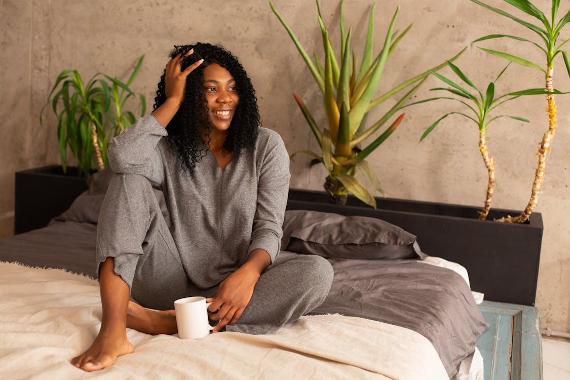 Free Photograph of a Woman in Gray Sleepwear Sitting on a Bed Stock Photo