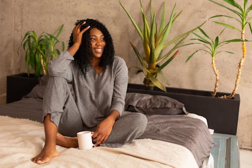 Free Photograph of a Woman in Gray Sleepwear Sitting on a Bed Stock Photo