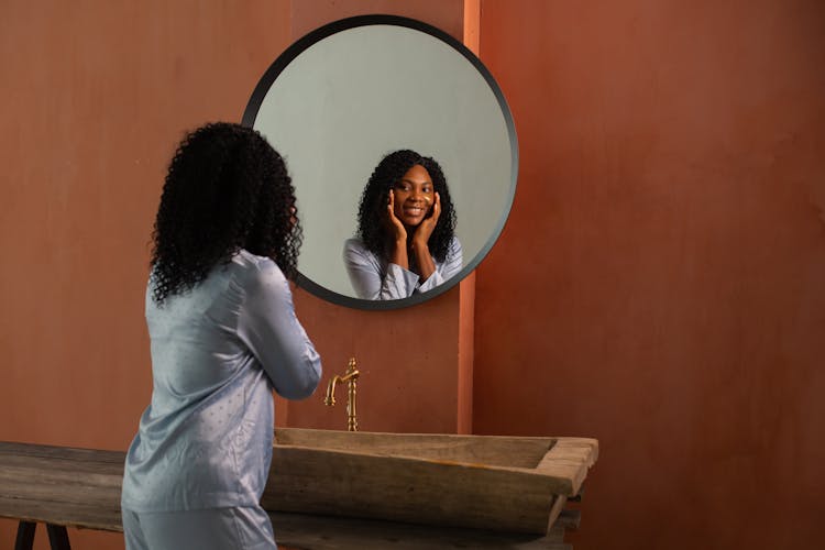 Woman In Pajamas Looking At Herself In The Mirror And Smiling 