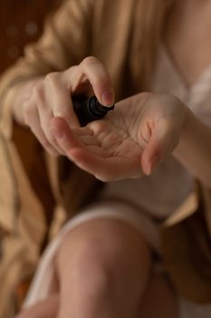 Close-up of hands applying skincare product from a spray bottle, highlighting self-care routine.