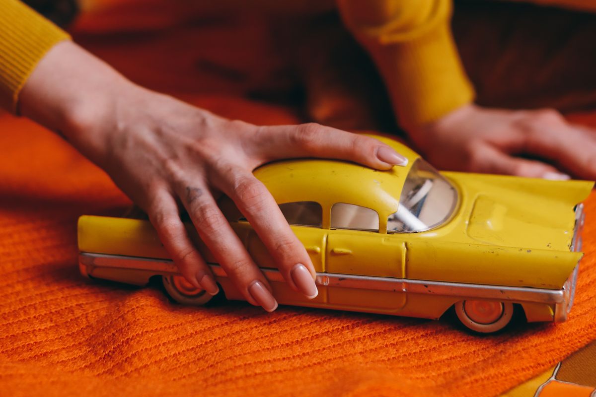 Pessoa segurando um pequeno carro de brinquedo antigo