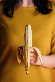 A woman holds a ripe banana, emphasizing healthy eating and nutrition.