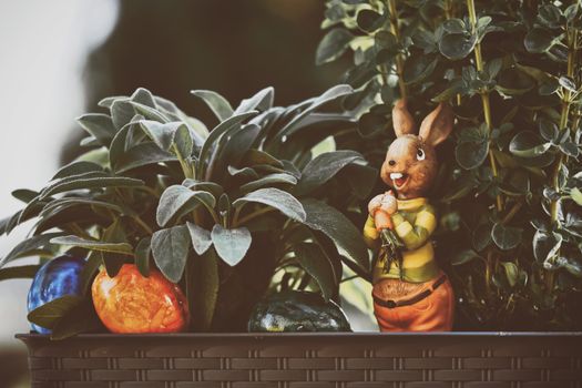 A delightful bunny figurine amongst colorful Easter eggs and potted greenery, perfect for holiday decor.