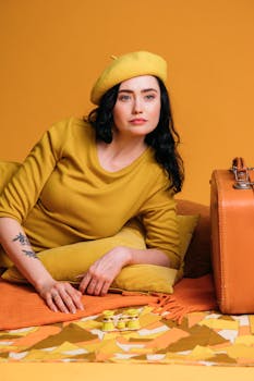 Creative portrait of a fashionable woman in yellow attire with a retro suitcase.
