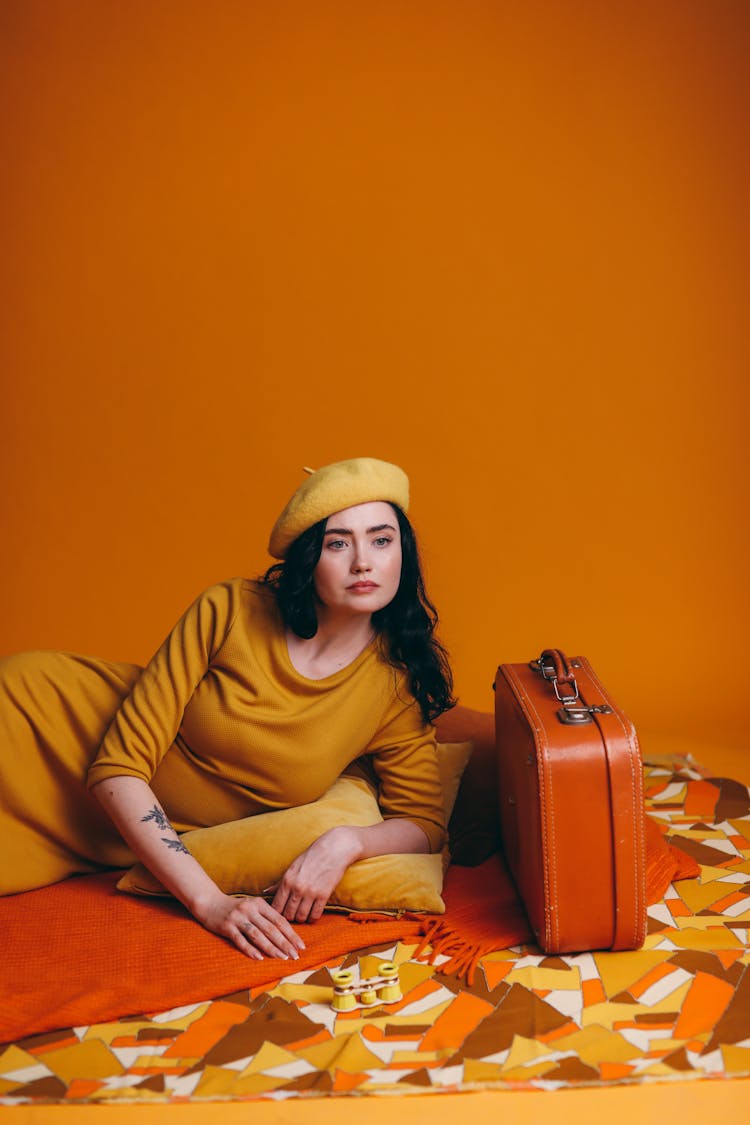 Woman In Yellow Outfit Beside A Suitcase