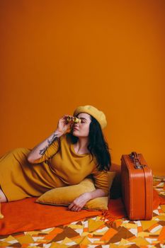 Fashionable woman in yellow against retro background with suitcase, embodies vintage travel style.
