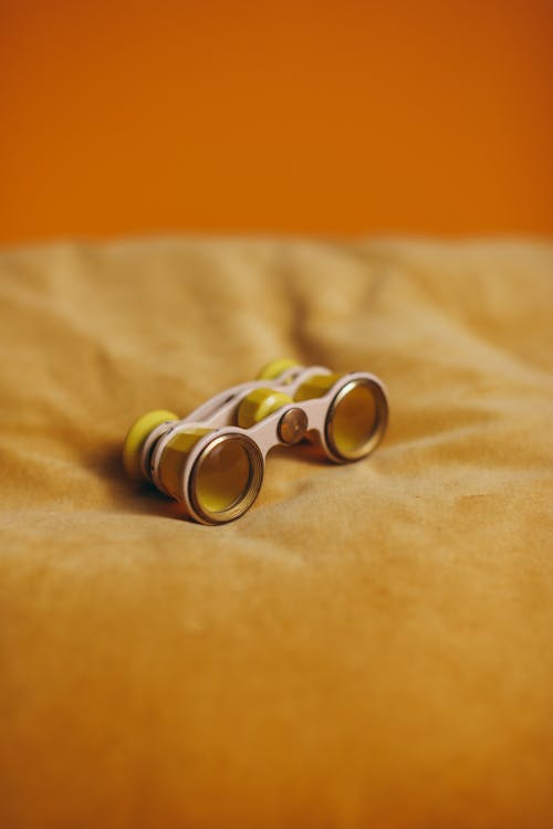 Yellow And Silver Binoculars on Yellow Textile