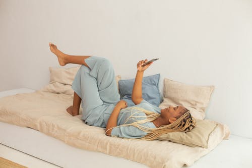 Woman Holding his Phone While Lying Down on Bed