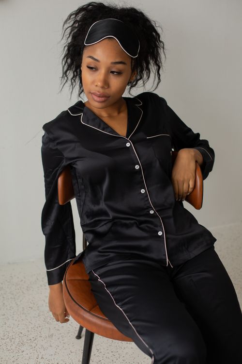 Free Portrait of a woman in elegant black silk sleepwear sitting indoors, adding a touch of luxury to nighttime relaxation. Stock Photo