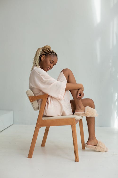 Free Side View of a Woman in Sleepwear Sitting on a Brown Chair Stock Photo