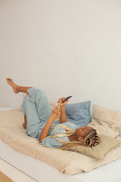 Woman in Blue Pajamas Lying on Bed