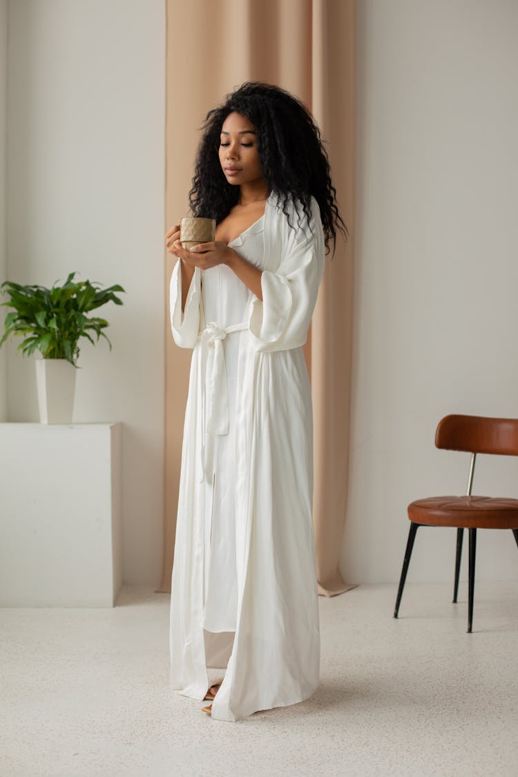 A Woman In White Robe Holding  A Mug