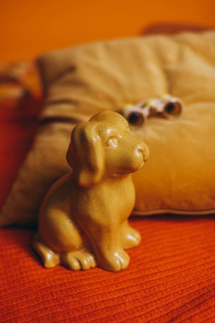 Yellow Ceramic Dog Figurine On Bed