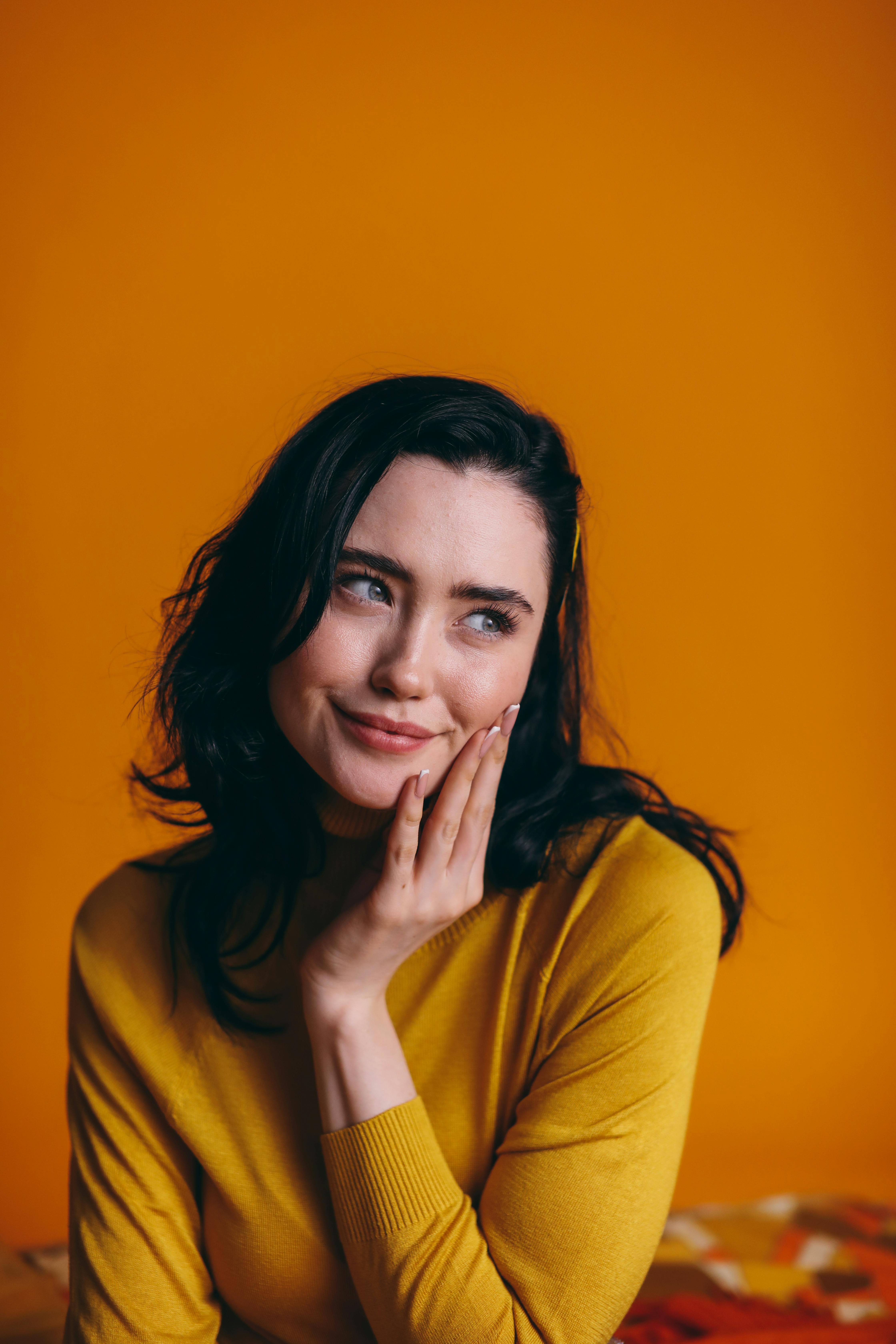 穿着黄色毛衣的迷人女子在充满活力的黄色背景下摆姿势