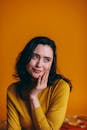 穿着黄色毛衣的迷人女子在充满活力的黄色背景下摆姿势