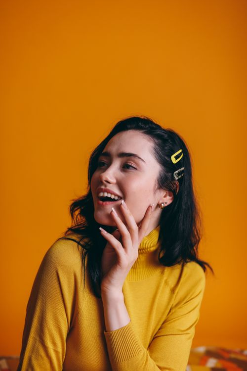 Free Creative portrait of a happy woman in a yellow outfit with a vivid yellow background. Stock Photo